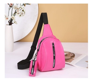 Detail of rose red chest bag with black adjustable strap and small hanging pouch