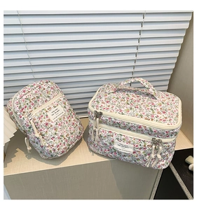 Detailed macro view of quilted floral makeup bags with beige zippers and woven labels