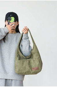 Macro shot of green corduroy shoulder bag showing fabric texture and leather label detail