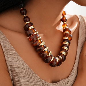 Close-up of retro acrylic beads and golden metal rings on a minimalist sweater chain
