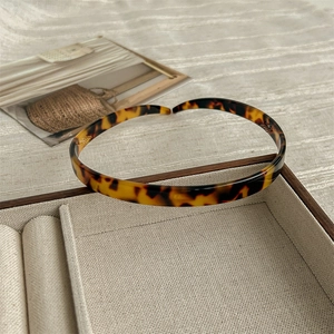 Detailed view of tortoiseshell resin headband resting on a rustic wooden display tray