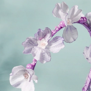 Close-up of purple fabric flower headband with white stamens and delicate purple beads