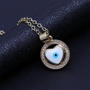 Macro view of gold plated heart pendant with blue evil eye and micro-set cubic zirconia