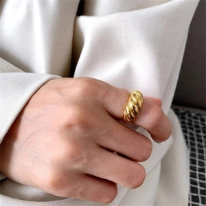 Close-up of a gold croissant twisted dome ring worn on finger for a French chic look