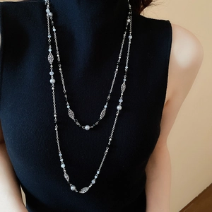 Detail of silver long multi-layer necklace with grey and black beads on black sweater