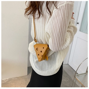 Mini yellow cheese-shaped leather crossbody bag worn by a model in a soft lit setting
