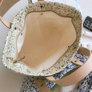 Detail view of floral tote bag with metal zipper closure and beige interior lining