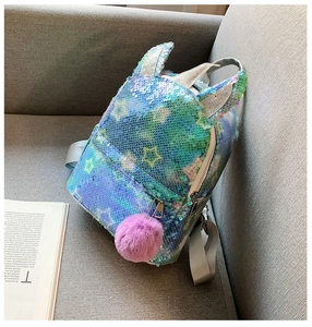 Detail of sequin backpack with star patterns, 3D ears and a purple fluffy pom pom charm
