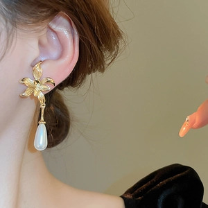 Elegant gold flower earrings with drop pearls shown on a model for a chic style