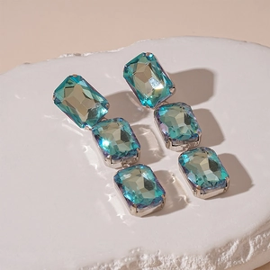 Detailed view of silver needle drop earrings with three rectangular blue gradient crystals