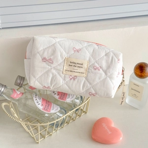 Détail de la trousse de toilette matelassée blanche avec nœuds roses et ruban