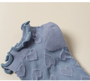 Close-up of light blue cotton socks featuring ruffle edges and embossed heart patterns