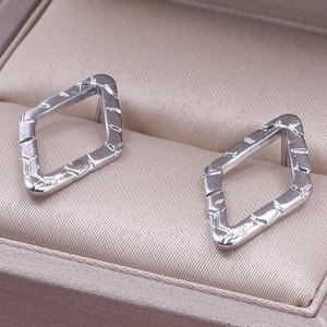 Macro shot of silver geometric diamond earrings with vintage textured engraving details