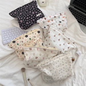 Flat lay of multiple embossed cotton makeup bags with floral and cartoon patterns on bed