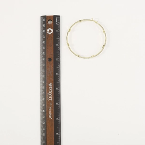 Dettaglio di un grande orecchino a cerchio dorato da 7,6 cm con strass e righello