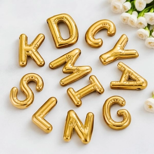 Polished gold bubble letter pendants on marble surface with white floral decor