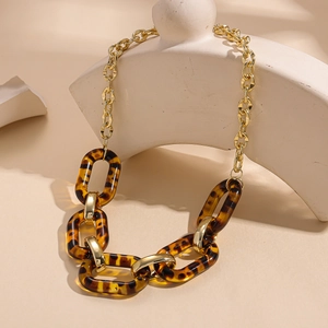 Detail of acrylic leopard print links and golden chain necklace on a geometric stand