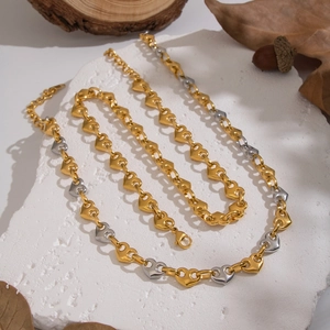 Two-tone mixed gold and silver heart-shaped link chain necklace on a textured stone base