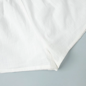 Detail of white cotton shorts hem showing clean stitching and natural fabric texture