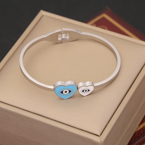 Polished stainless steel evil eye heart bangle displayed on a beige jewelry gift box
