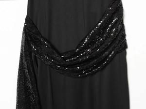 Close-up detail of a black midi dress featuring a wide belt adorned with shiny black sequins