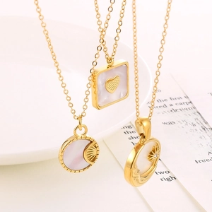 Drie gouden geometrische kettingen met schelp-inleg op een wit keramisch bord