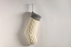 Close-up of cream knit Christmas stocking featuring classic cable stitch and grey ribbed cuff