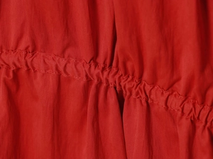Vue macro du tissu rouge d'une robe midi montrant des fronces et coutures précises