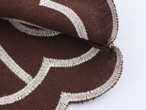 Close-up of ethnic embroidered brown trousers showing fabric texture and wavy stitching