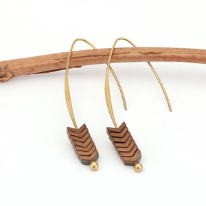 Macro detail of vintage gold hook earrings with five brown arrow beads on a wood branch