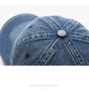Detailed close-up of blue washed denim baseball cap with reinforced stitching and eyelets