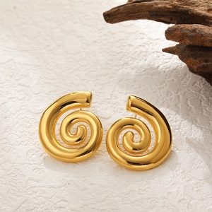Macro view of gold spiral earrings with polished finish on textured stone background