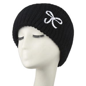 Gros plan sur un bonnet en maille noire avec nœud blanc brodé élégant