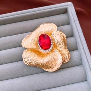 Close-up of floral brooch with red gemstone and crystal petals in jewelry box