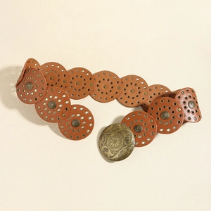 Detail of brown leather belt with circular metal eyelets and ornate bronze buckle