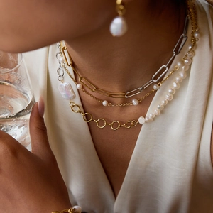 Close-up of a model wearing a gold and silver pearl necklace set with matching earrings