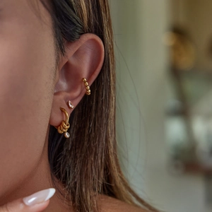 Detailed view of gold plated earrings set with zircon studs and delicate ear cuffs