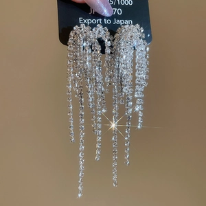 Macro detail of silver needle tassel earrings with sparkling rhinestones and crystal finish