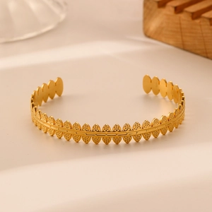Detail of vintage golden open bangle featuring an intricate leaf texture and grain finish