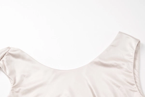 Close-up of champagne satin dress showing U-neckline detail and smooth silk texture