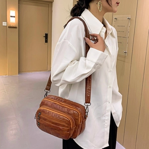 Sac bandoulière en cuir souple marron avec plusieurs fermetures éclair porté par un mannequin