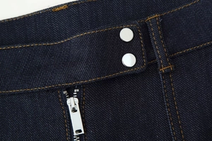 Détail macro de la taille d'un jean en denim bleu foncé avec boutons et coutures orange
