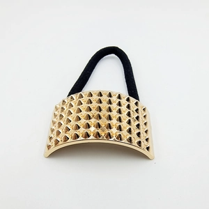 Detail of a gold studded metallic cuff on a black elastic hair tie with punk rivet design