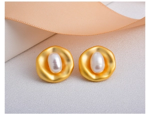 Detailed macro view of an irregular matte gold earring with an oval freshwater pearl inlay