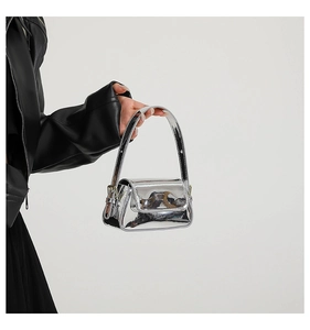 Detail of metallic silver crossbody bag with a glossy mirror finish and single handle