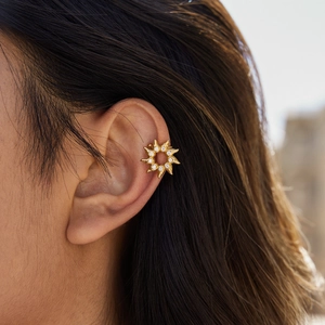 Close-up of a gold sun flower ear cuff with sparkling zircon stones worn by a model