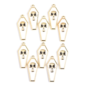 Macro view of ten gold vampire coffin skull pendants with white enamel on a white background