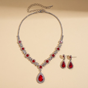 Detailed close-up of vintage necklace and earring set with red teardrop rhinestones