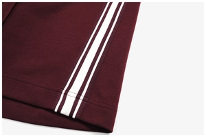 Close-up of burgundy athletic jacket sleeve with classic white triple stripes detailing