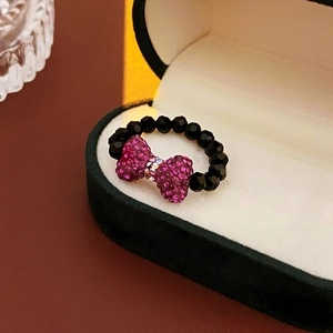 Detail of beaded ring featuring a pink rhinestone bow and black multifaceted crystals